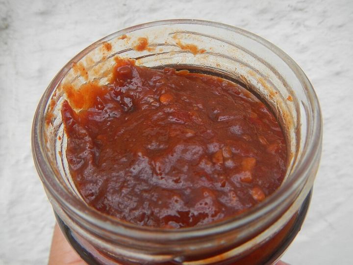A glass jar of dark red chilli bean paste (doubanjiang), thick and chunky