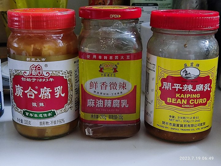 Three glass jars of fermented tofu with red lids and printed labels