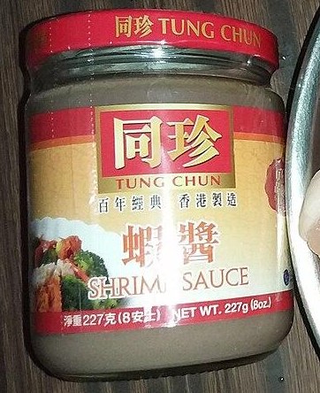 A glass jar of shrimp sauce with a red lid and a Tung Chun label